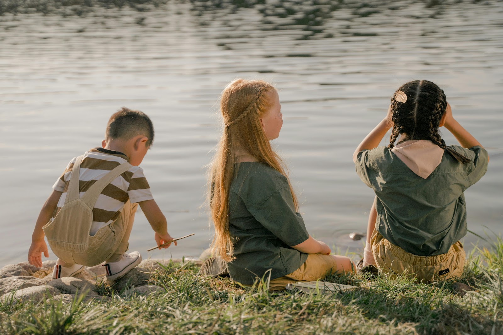 curious-kids-by-lake-promoting-curiosity-and-learning kids-sitting-by-lake-exploring-nature-and-learning