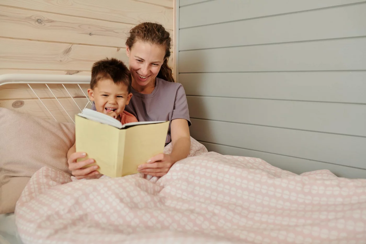 Mother and son reading together in a cozy bedroom, sharing positive parenting tips through bonding time