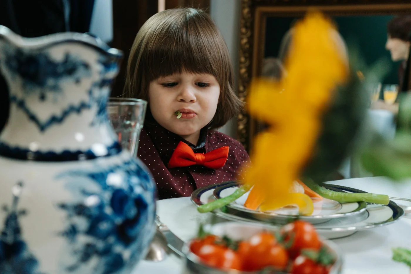Young child making a funny face while trying vegetables, showing simple meals for fussy eaters at the table
