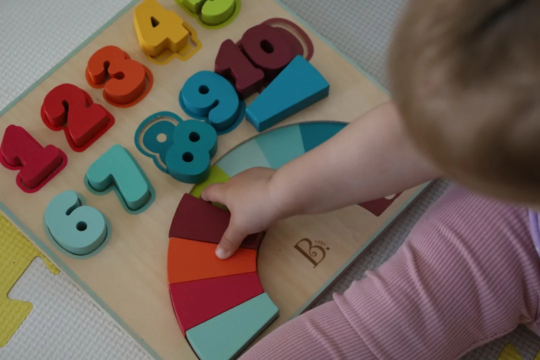 Child playing with a wooden toy while parents learn what are physical development milestones and red flags
