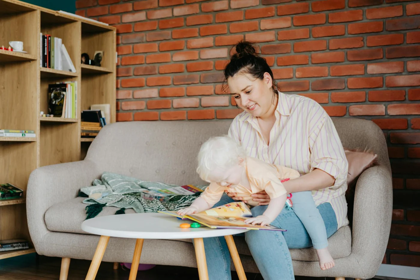 Mother reads to her baby on a cozy sofa, showing what are the benefits of reading aloud every day