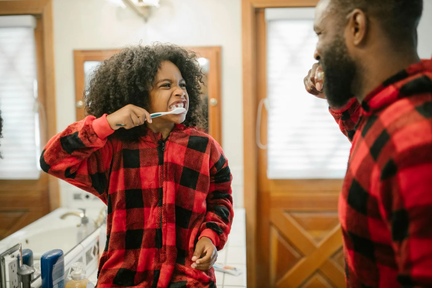 Father and daughter brush their teeth together, showing what is gentle parenting through calm daily habits