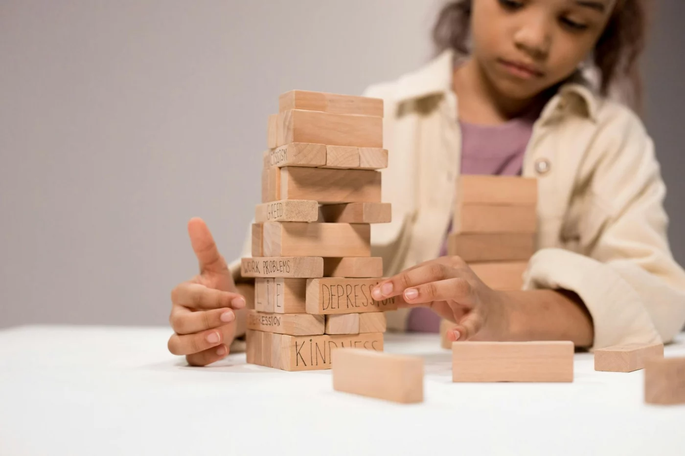 Child stacking blocks labeled depression and kindness, showing why is it important to develop emotional intelligence