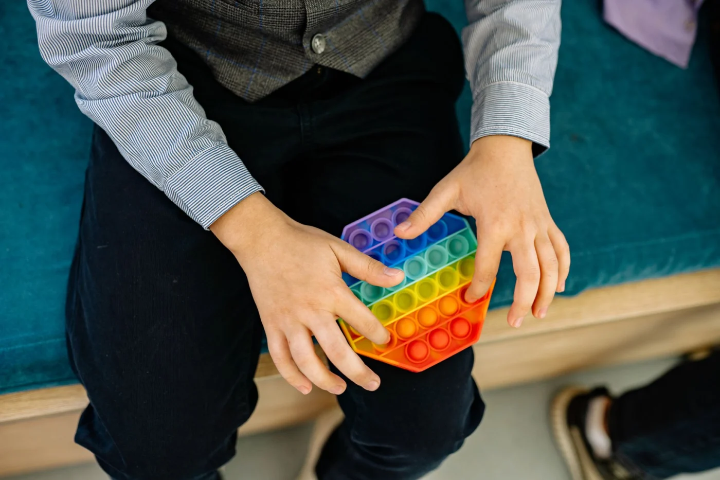Child using a rainbow pop it as part of calm sensory play